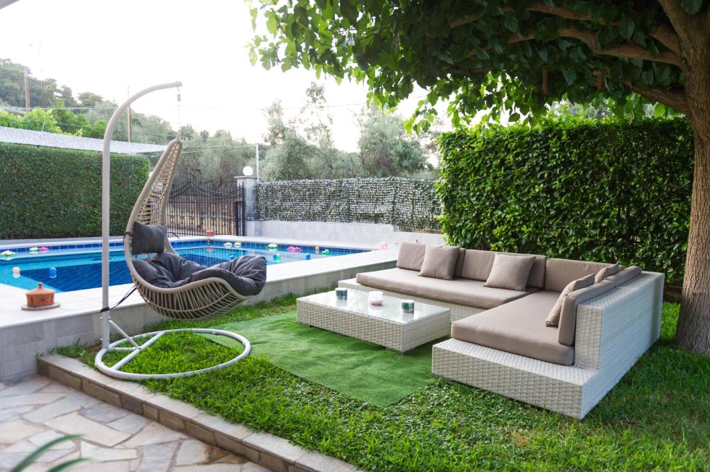 patio trasero con sofá y hamaca junto a la piscina en Luxurious Villa Anastasia, en Zíria
