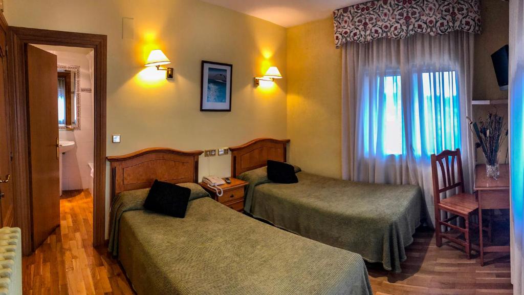 a hotel room with two beds and a window at Hotel A Nieu in Jaca