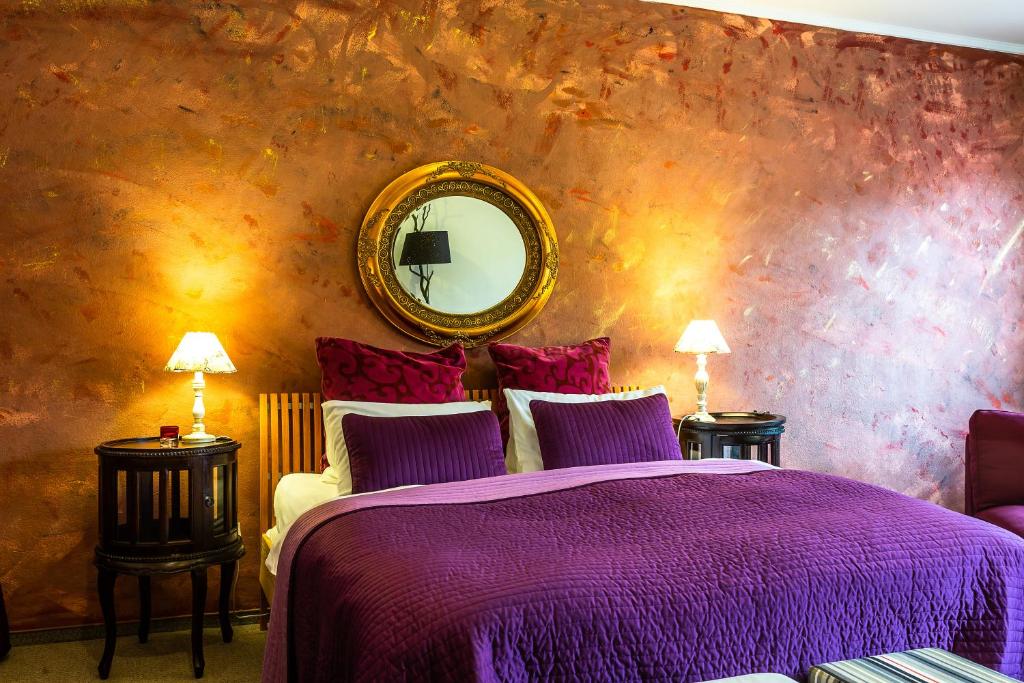 a bedroom with a purple bed and a mirror at Penzion Veza in Kremnica
