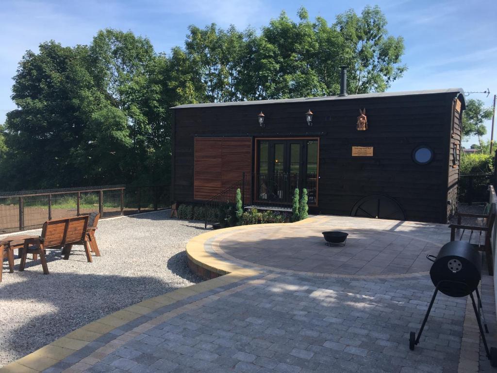 a small black building with two benches in a patio at Gorestown Glamping Chalets in Drummond