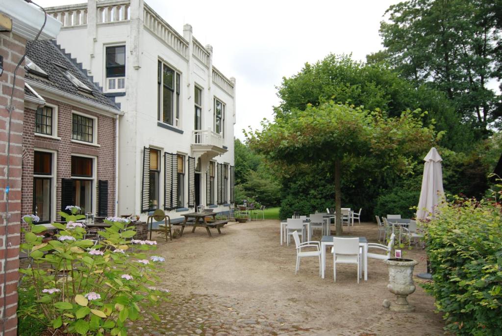 une cour avec des tables et des chaises et un bâtiment dans l'établissement De Jufferen Lunsingh, à Westervelde