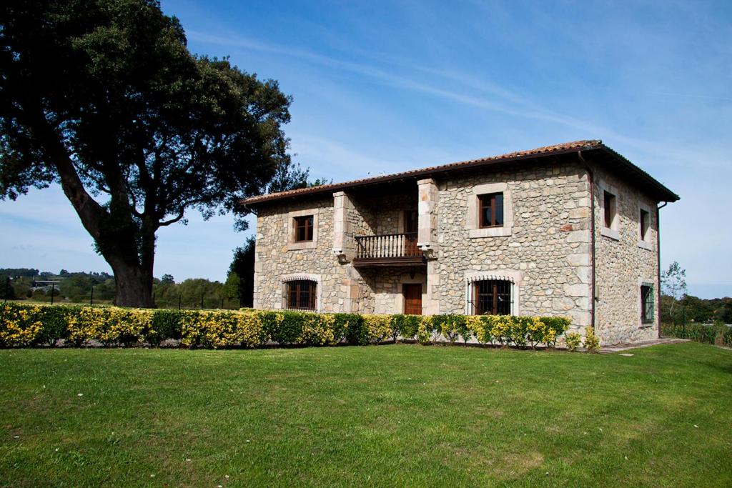 un gran edificio de piedra con un árbol en el fondo en Casa de Aldea la Piniella, en Villahormes