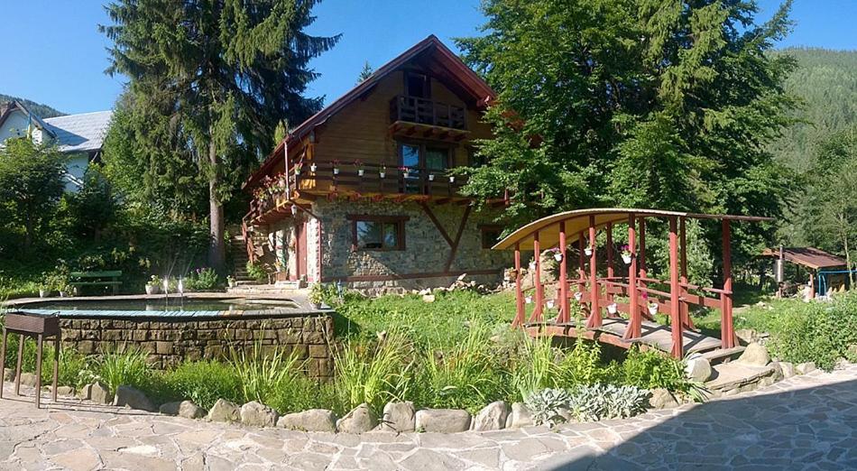 a log cabin with a pond in front of a house at садиба "У Наталії" in Tatariv