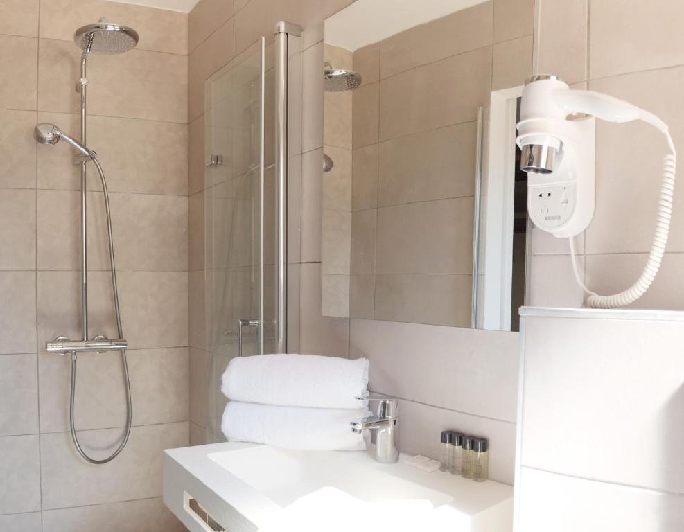 a bathroom with a shower and a sink and a mirror at Hotel La Voile in Bormes-les-Mimosas