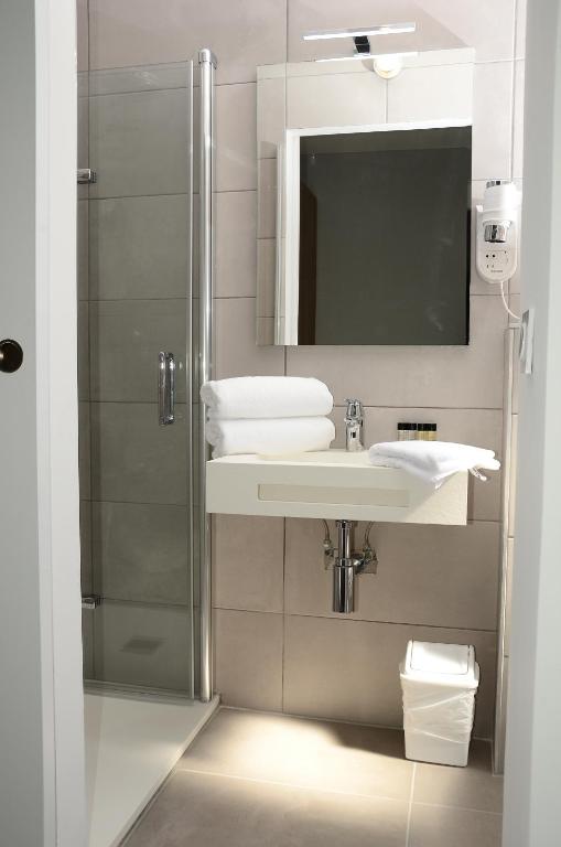 a bathroom with a shower and a sink and a mirror at Hotel La Voile in Bormes-les-Mimosas