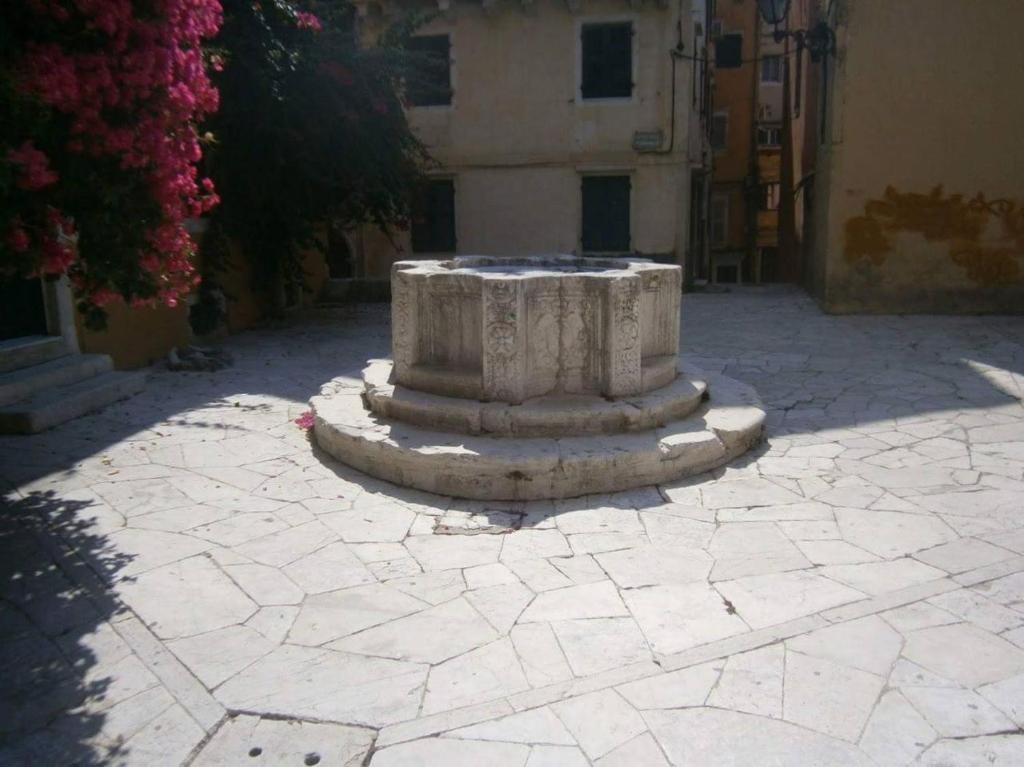 a stone fountain in the middle of a courtyard at The well in Corfu