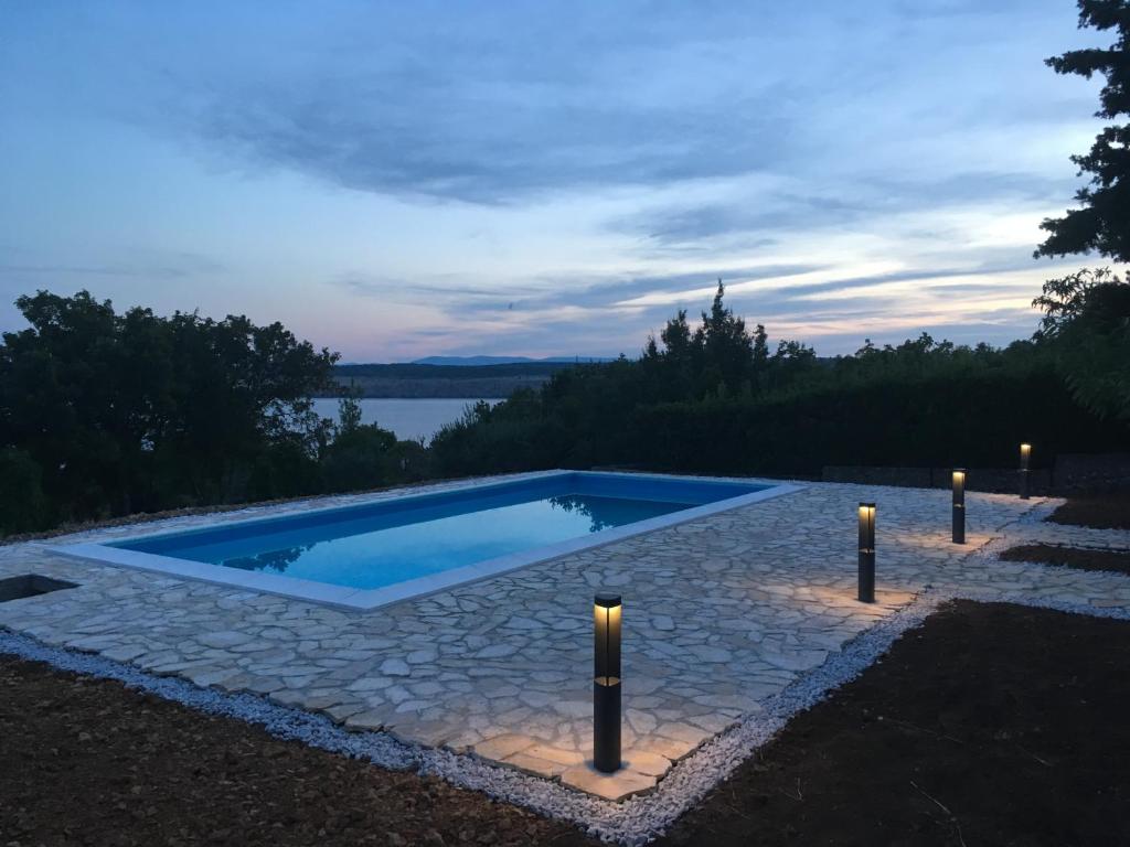 - une piscine avec des lumières près d'un corps d'eau dans l'établissement Villa Pinia Holiday home with a pool, à Jadranovo