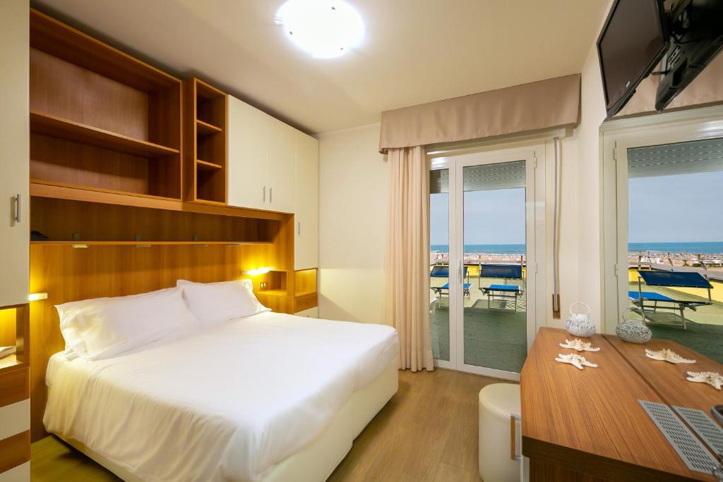 a bedroom with a bed and a desk and a window at Hotel Verona in Caorle