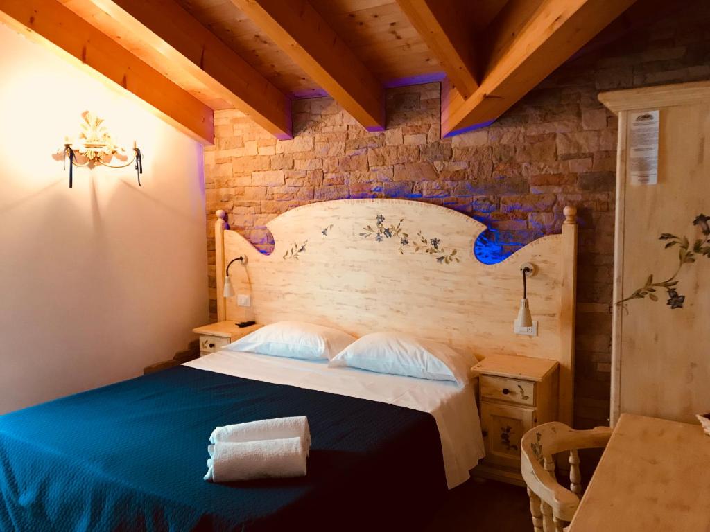 a bedroom with a bed and a brick wall at B&B Le Coccole in Molveno