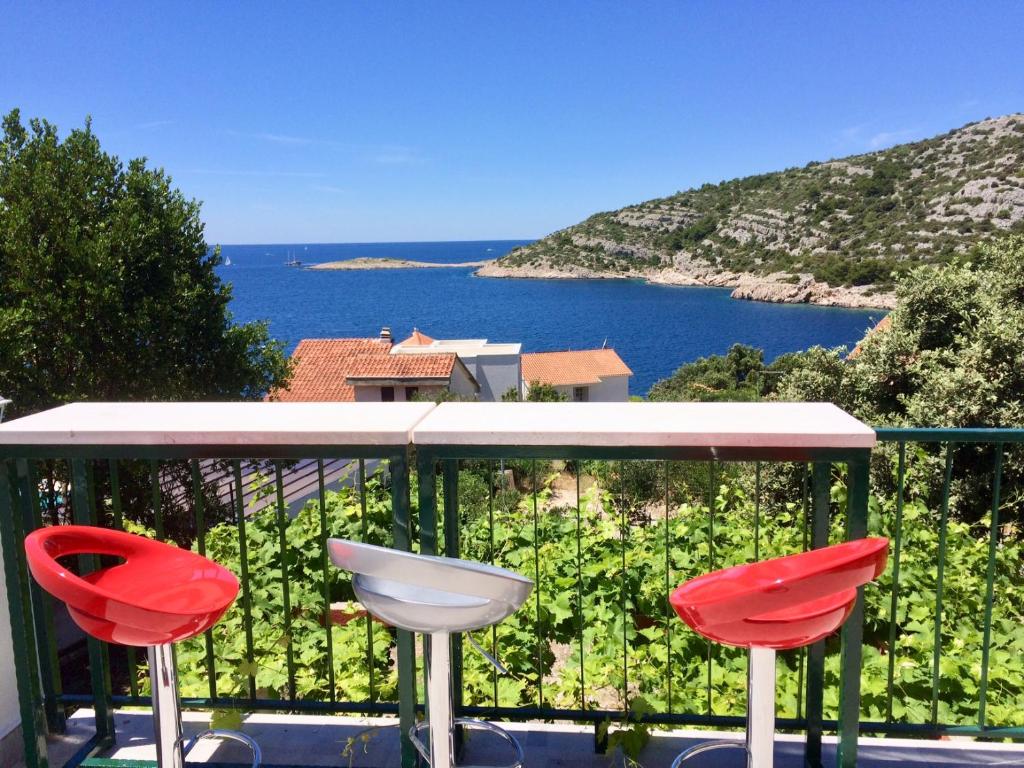 balcón con 2 sillas rojas y vistas al océano en Villa Luna en Ražanj