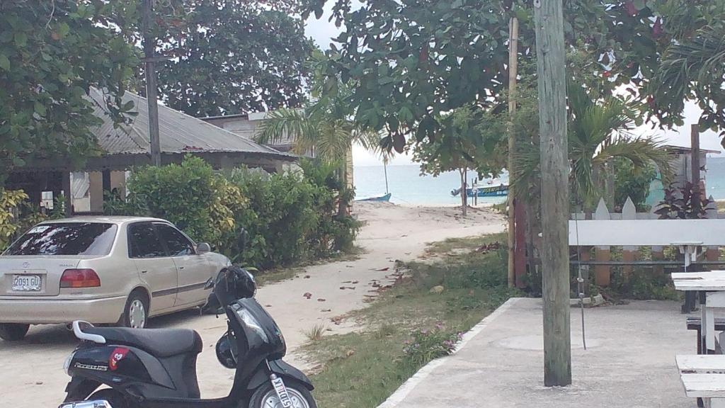 a motorcycle parked next to a car next to the beach at Drifters@One Mile in Negril