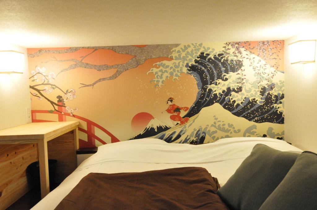 a bedroom with a painting of a wave on the wall at NASUBI Mt. Fuji Backpackers in Fuji