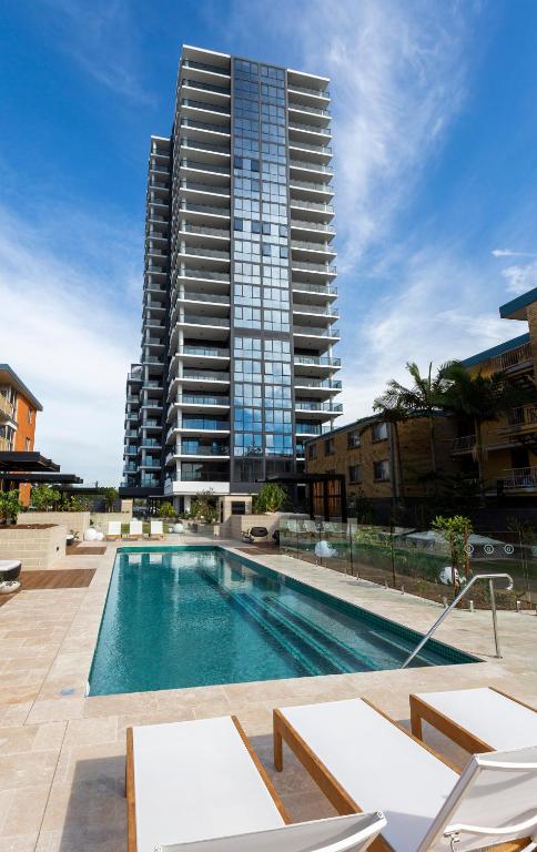 a swimming pool with a tall building in the background at Boardwalk Burleigh Beach - Official in Gold Coast