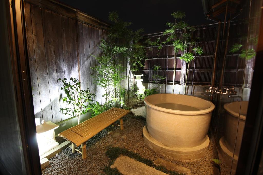 a bathroom with a tub and a bench and plants at LiB PLUS Kyoto Maiko Han-inn in Kyoto