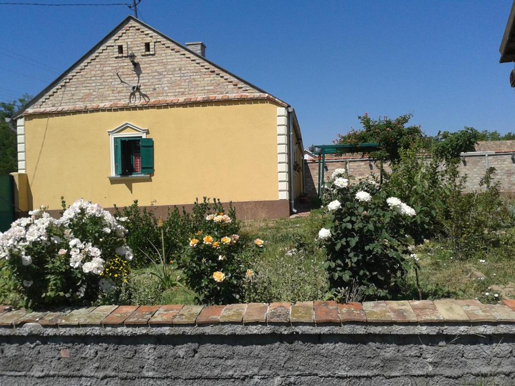 a yellow house with a window and some flowers at Lovačka kuća in Veliko Središte