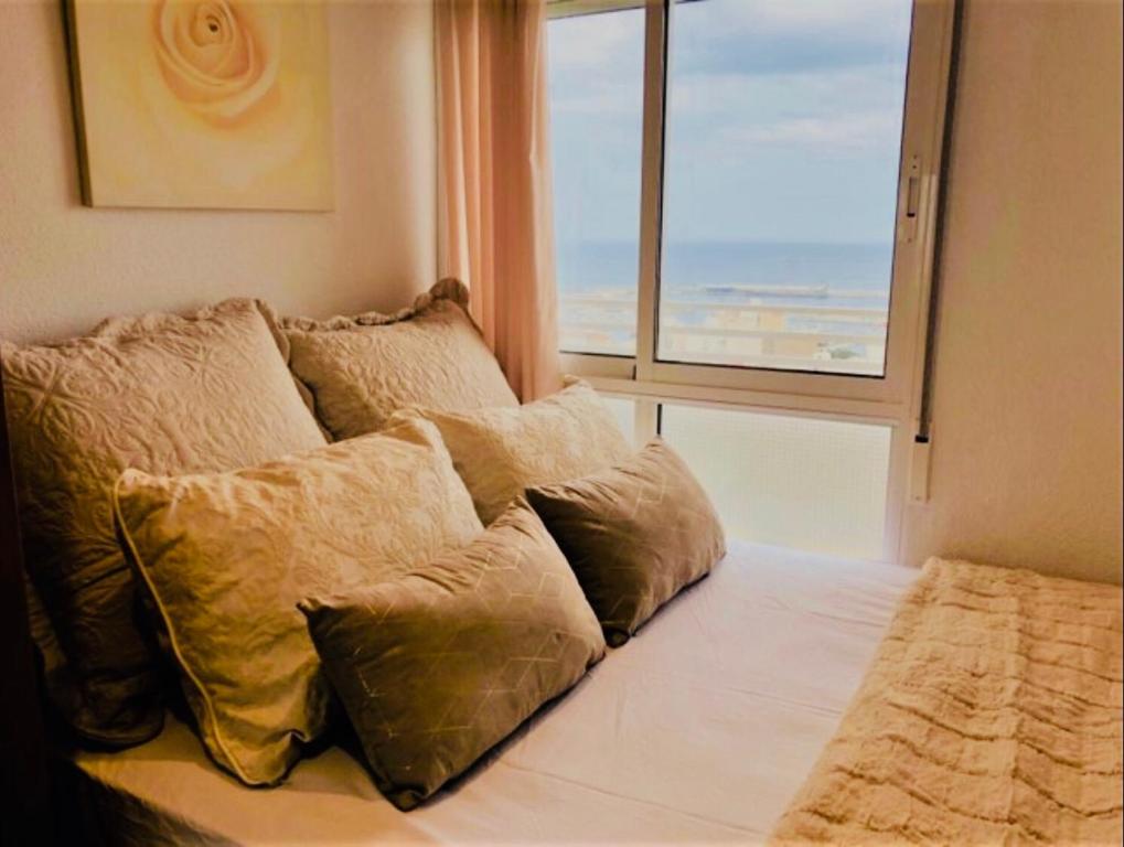 Cama con almohadas en habitación con ventana en Apartamento & sea view en Alicante