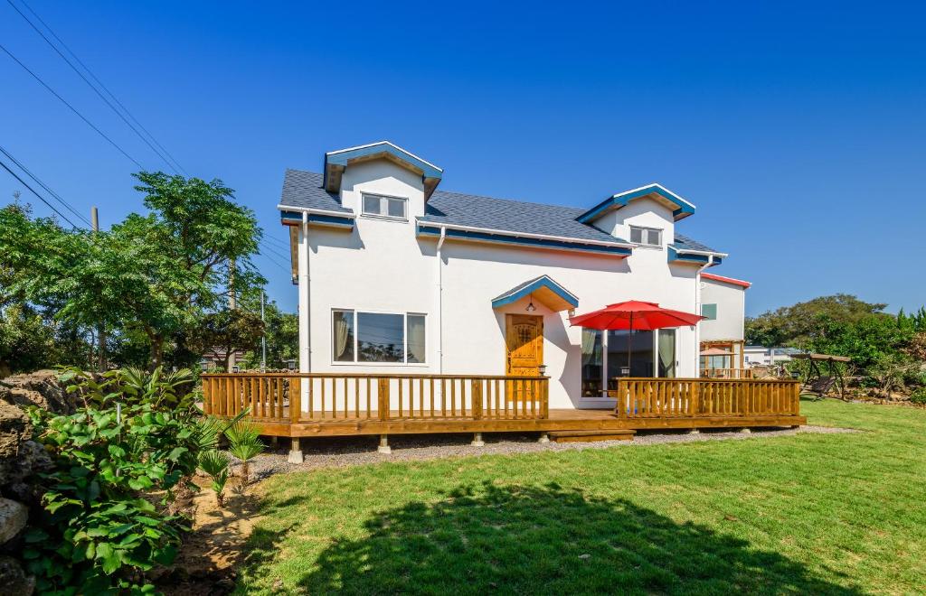 a white house with a deck with a red umbrella at Atempause in Jeju
