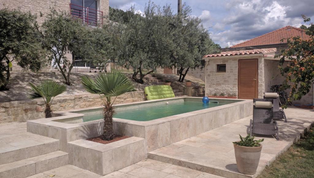 a swimming pool in a yard with trees and a house at Le Mas de la Tortue (Plain Pied) in Caromb