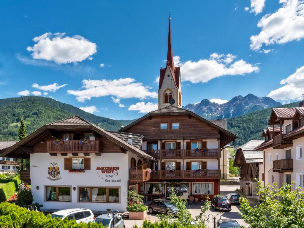 a building in the mountains with a church at Geniesserhotel Messnerwirt Olang in Valdaora