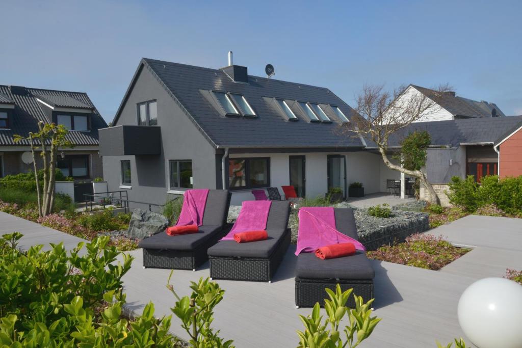zwei schwarze Stühle mit rosa Kissen auf einer Terrasse in der Unterkunft Haus Sathurn in Helgoland