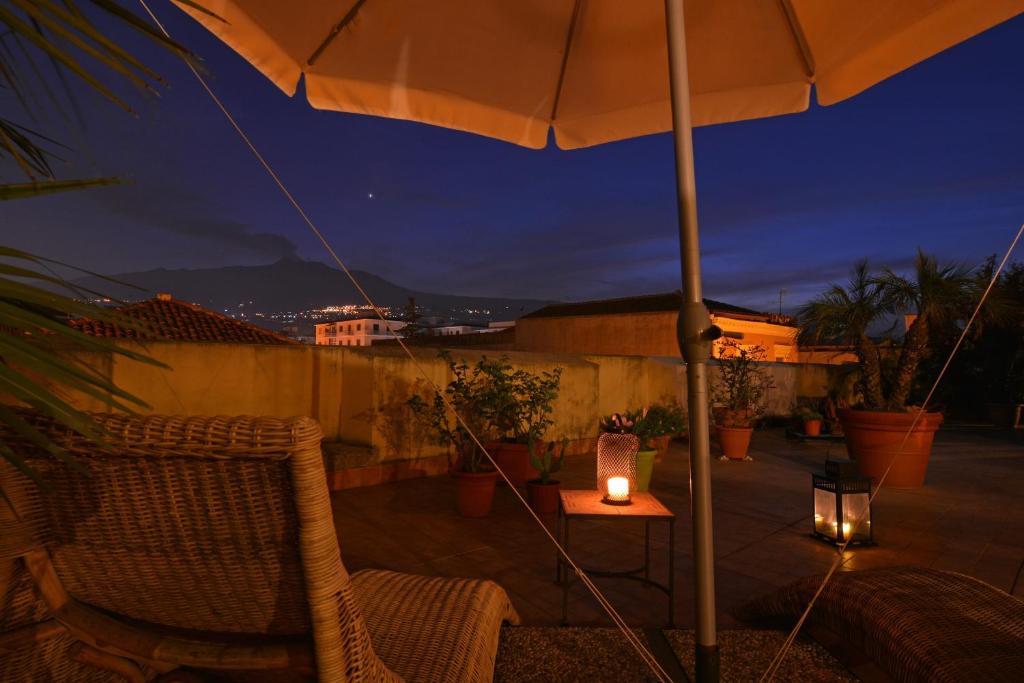 un patio con una sombrilla y una mesa con una vela en B&B di Charme Camelie, en Riposto