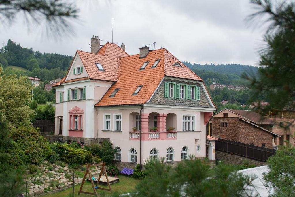 une grande maison blanche avec un toit orange dans l'établissement Penzion Signum Laudis, à Velké Hamry