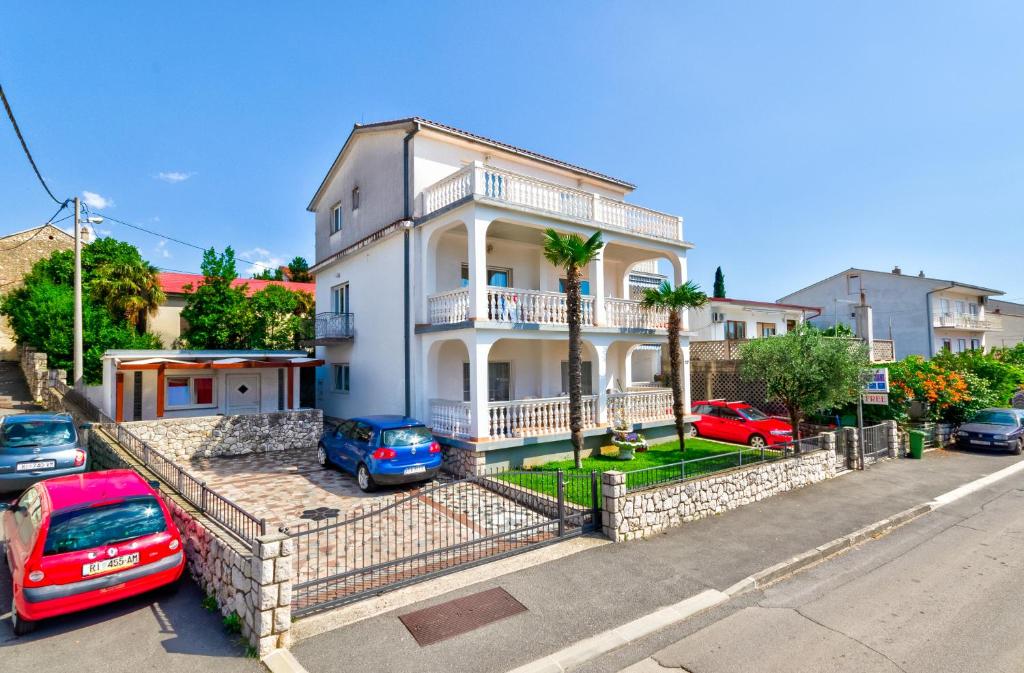 une maison blanche avec des voitures garées devant elle dans l'établissement Apartments Vukovic, à Selce
