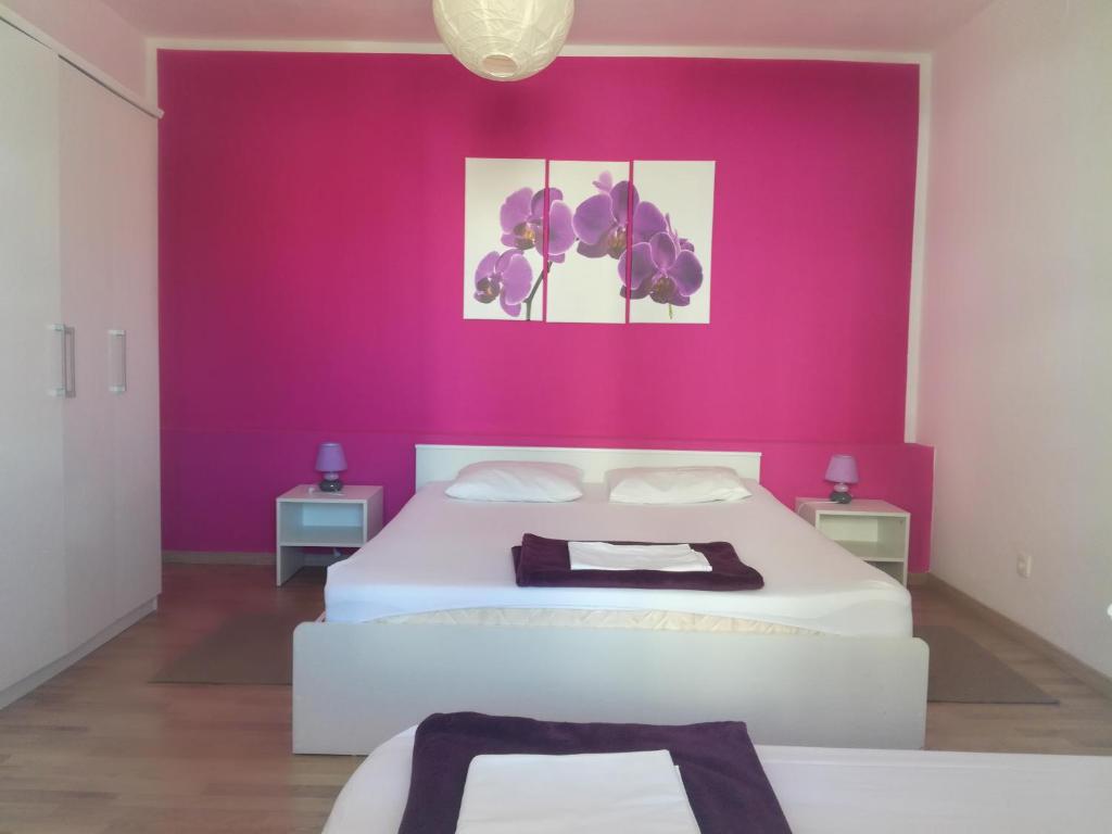 - une chambre avec 2 lits et un mur rose dans l'établissement Dama Apartment, à Biograd na Moru