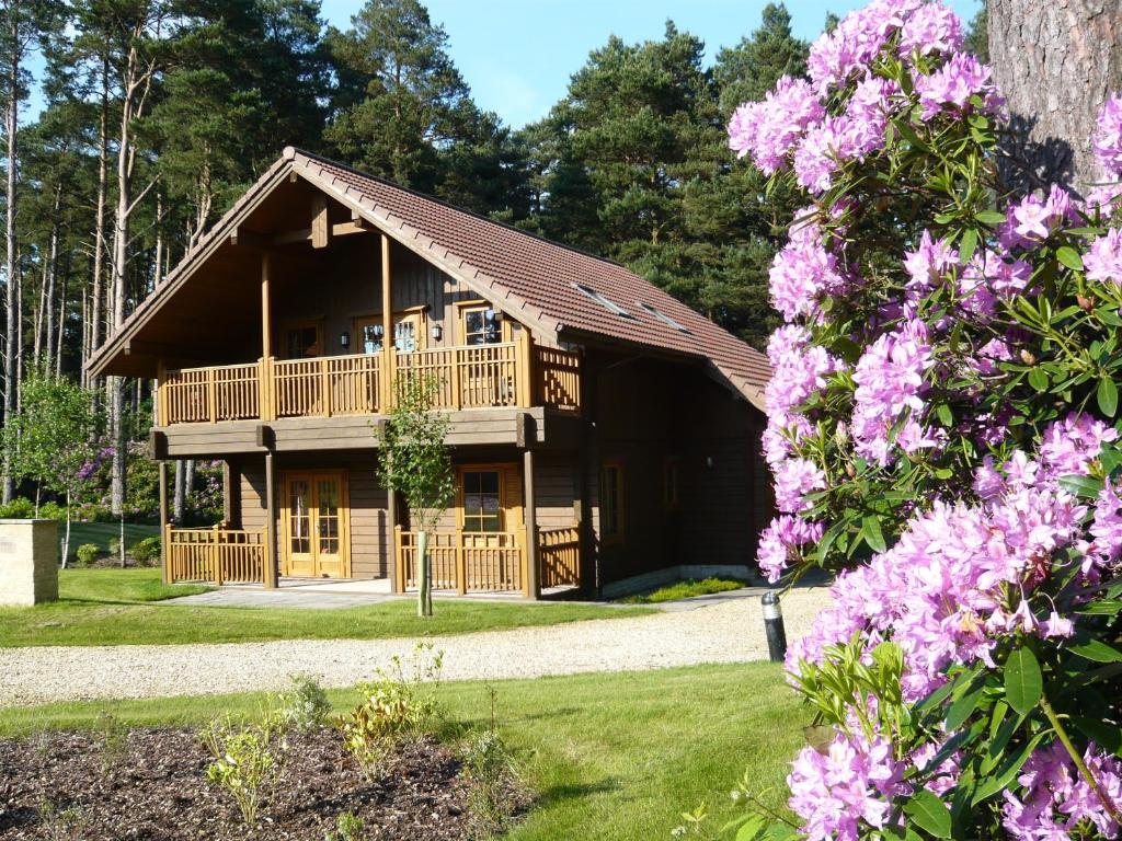 una cabaña de madera con flores rosas delante en The Dorset Resort en East Stoke