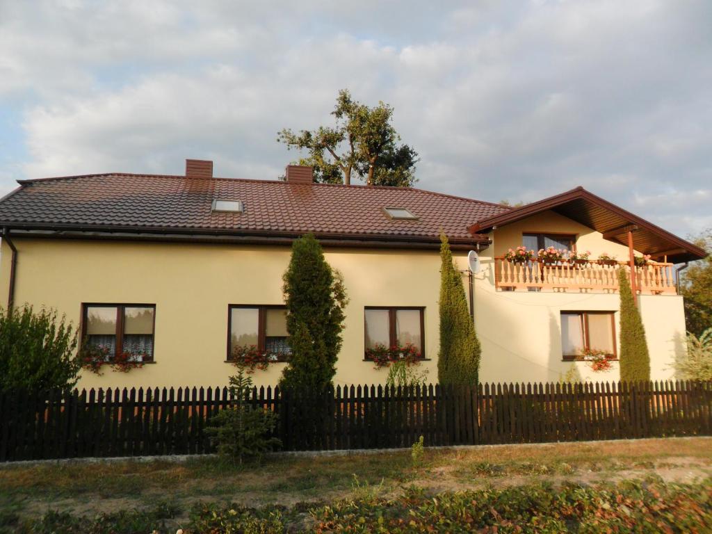 ein Haus mit einem Zaun und einem Balkon in der Unterkunft Maciejówka Gospodarstwo Agroturystyczne in Poddębice