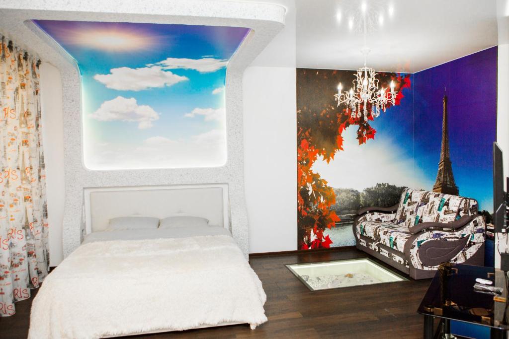 een slaapkamer met een wit bed en een kroonluchter bij Apartment Kristall at Leningradskaya 46 in Yurga