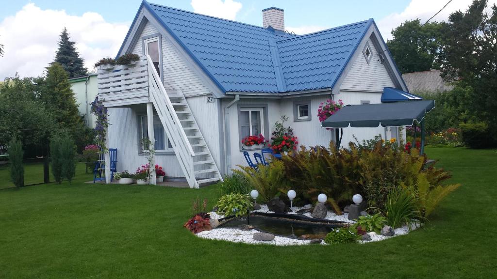 a white house with a blue roof and a fountain at Luha Private House in Pärnu