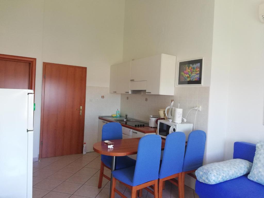 a kitchen with a table and blue chairs in a room at Apartmani Marija in Primošten