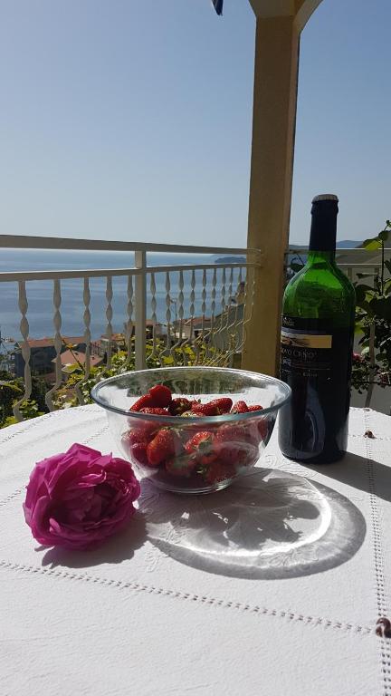 a bowl of strawberries on a table with a bottle of wine at Apartmani Famelja Jovanovic in Sveti Stefan