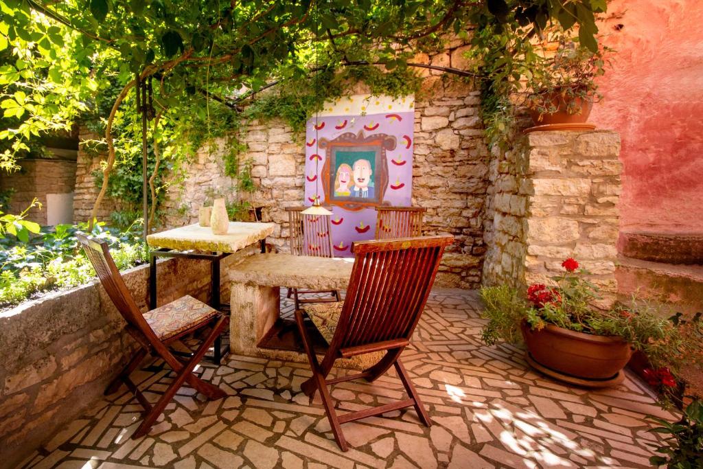 a patio with two chairs and a table in a garden at Kamene Priče rooms, music and food in Bale