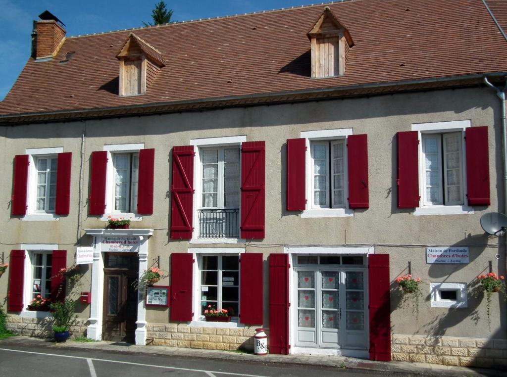 un bâtiment avec volets rouges dans une rue dans l'établissement Maison de Fortitude Chambres d'hotes, à Salviac