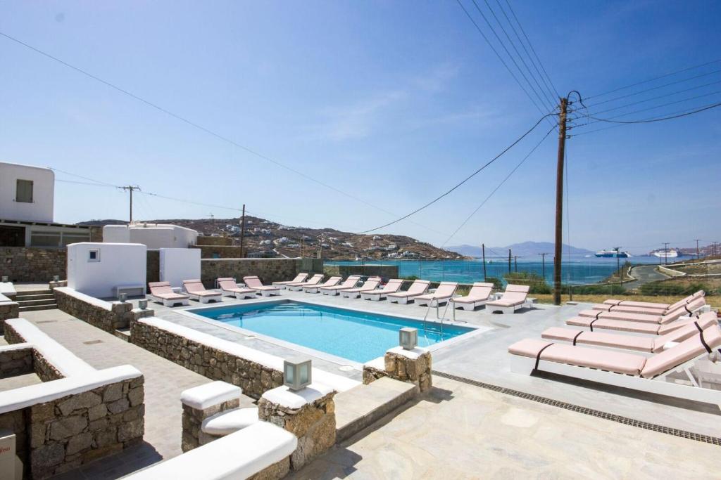 - une piscine avec des chaises longues et l'océan dans l'établissement Anixi Hotel, à Ornos