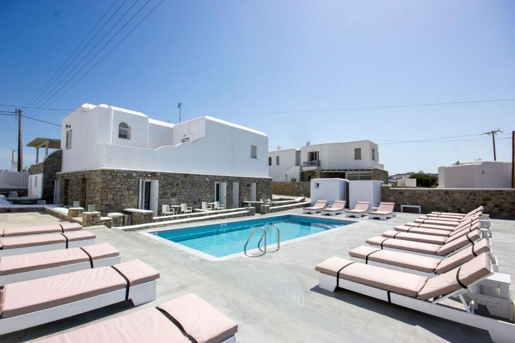 uma villa com uma piscina e espreguiçadeiras em Anixi - Primavera Mykonos em Ornos