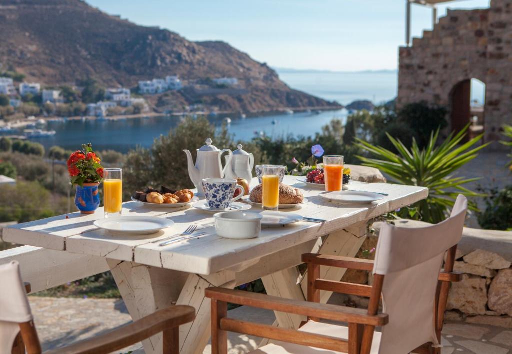 a table with a breakfast of orange juice and a view of the ocean at Theologos Houses in Grikos
