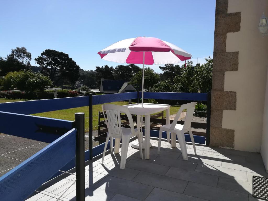 a table and chairs with an umbrella on a balcony at Ti Jaclou in Trébeurden