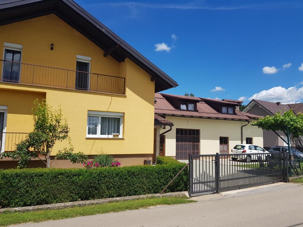 a yellow house with a fence in front of it at Apartman DIVA in Otočac