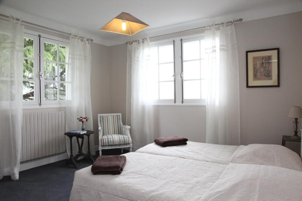 a bedroom with two beds and a chair and windows at Gure Lana in Saint-Jean-Pied-de-Port