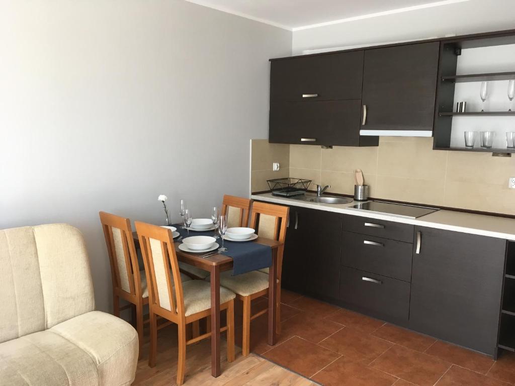 kuchnia ze stołem i krzesłami oraz blatem kuchennym w obiekcie Apartamenty Zielona Wydma w Łebie