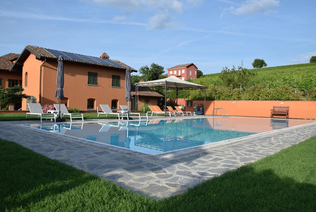 uma piscina num quintal com cadeiras e uma casa em Cascina dei Giacinti em Nizza Monferrato