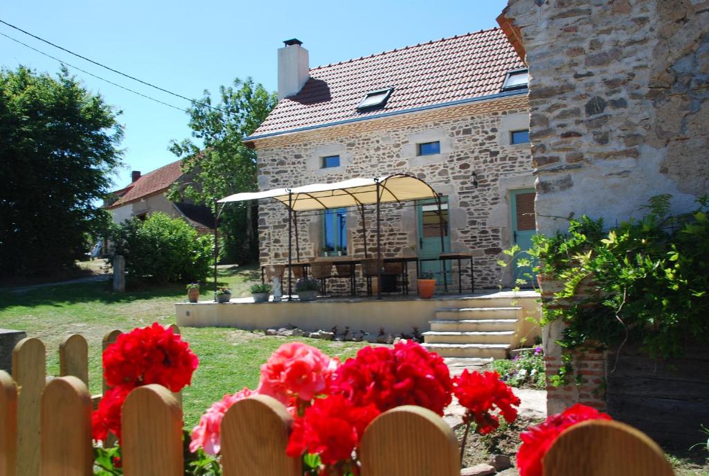 a fence in front of a house with red flowers at Chambres d'Hôtes Maison Balady in Bellenaves