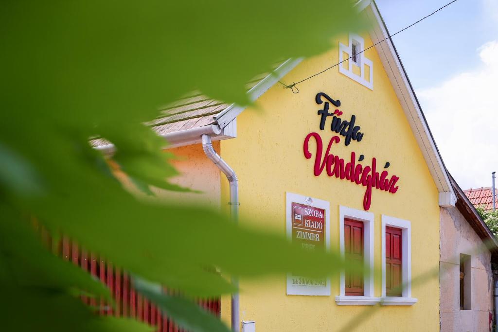 un edificio amarillo con escritura roja en el costado. en Fűzfa Vendégház, en Bogács