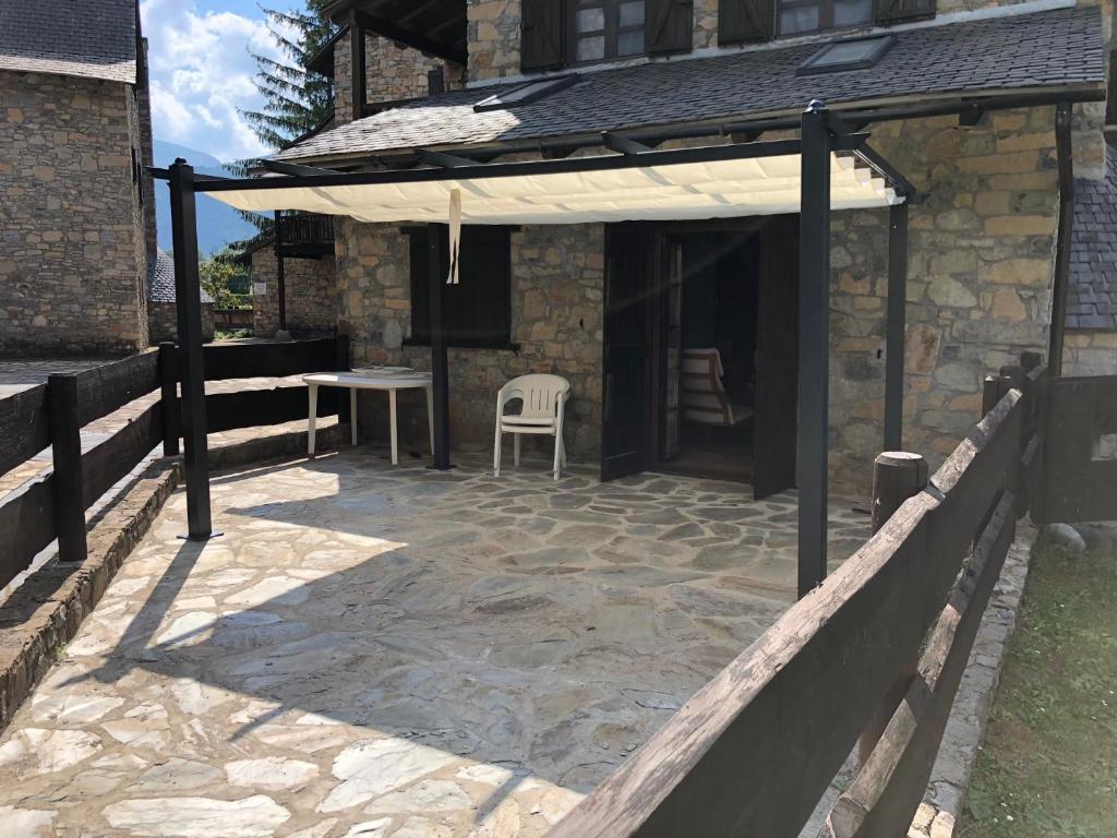 a patio with a white umbrella and a chair at Alacran Home in Benasque