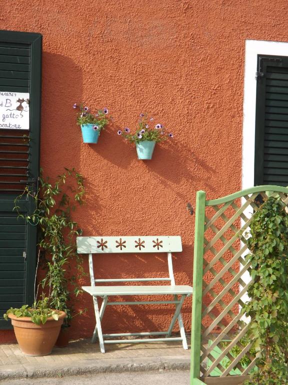 a white bench sitting next to a wall with plants at B&B Il Gatto Pescatore in Stintino