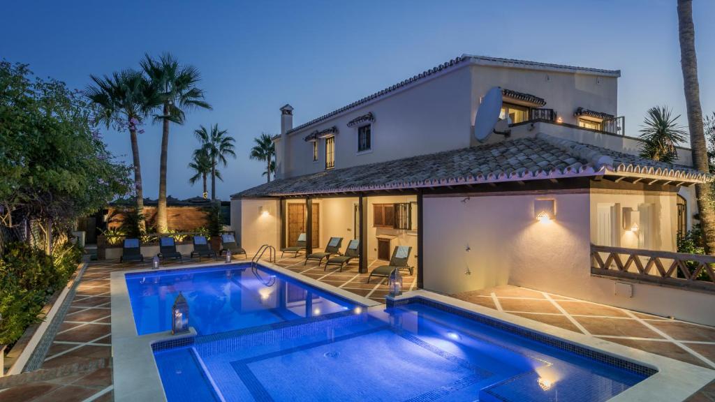 a villa with a swimming pool in front of a house at The Residence by the Beach House Marbella in Marbella