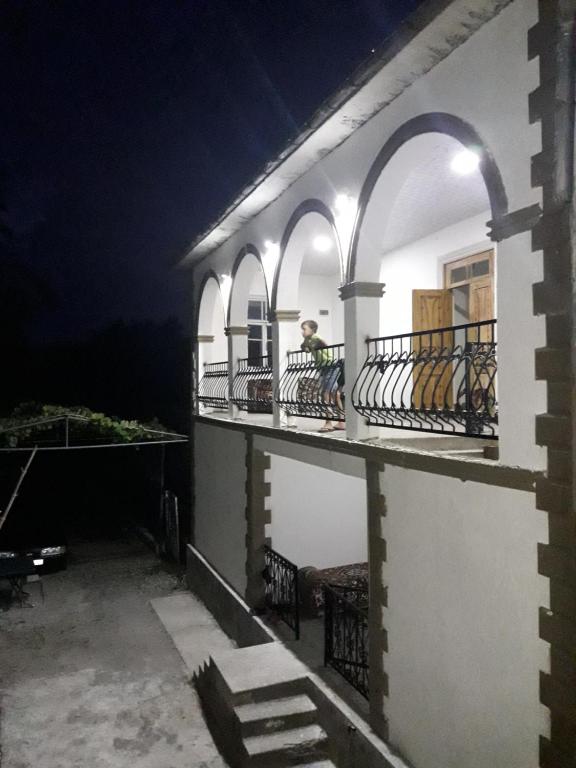 a man sitting on a balcony at night at House Dea Dea in Chakvi